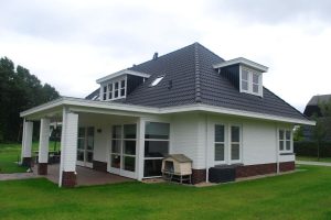 Wit huis met zwarte dakpannen en een veranda.