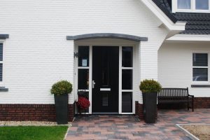 Wit huis met zwarte dakpannen en een veranda.