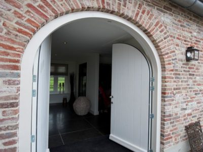 Een ingang van een woning met boogdeuren